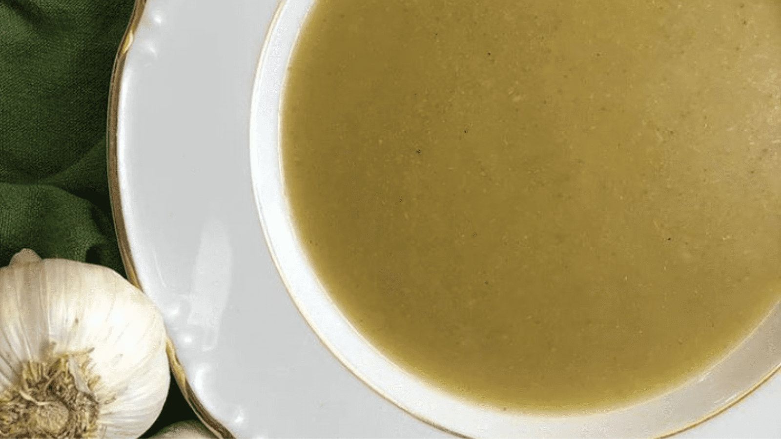 Parsnip and broccoli soup in a bowl with garlic at the side